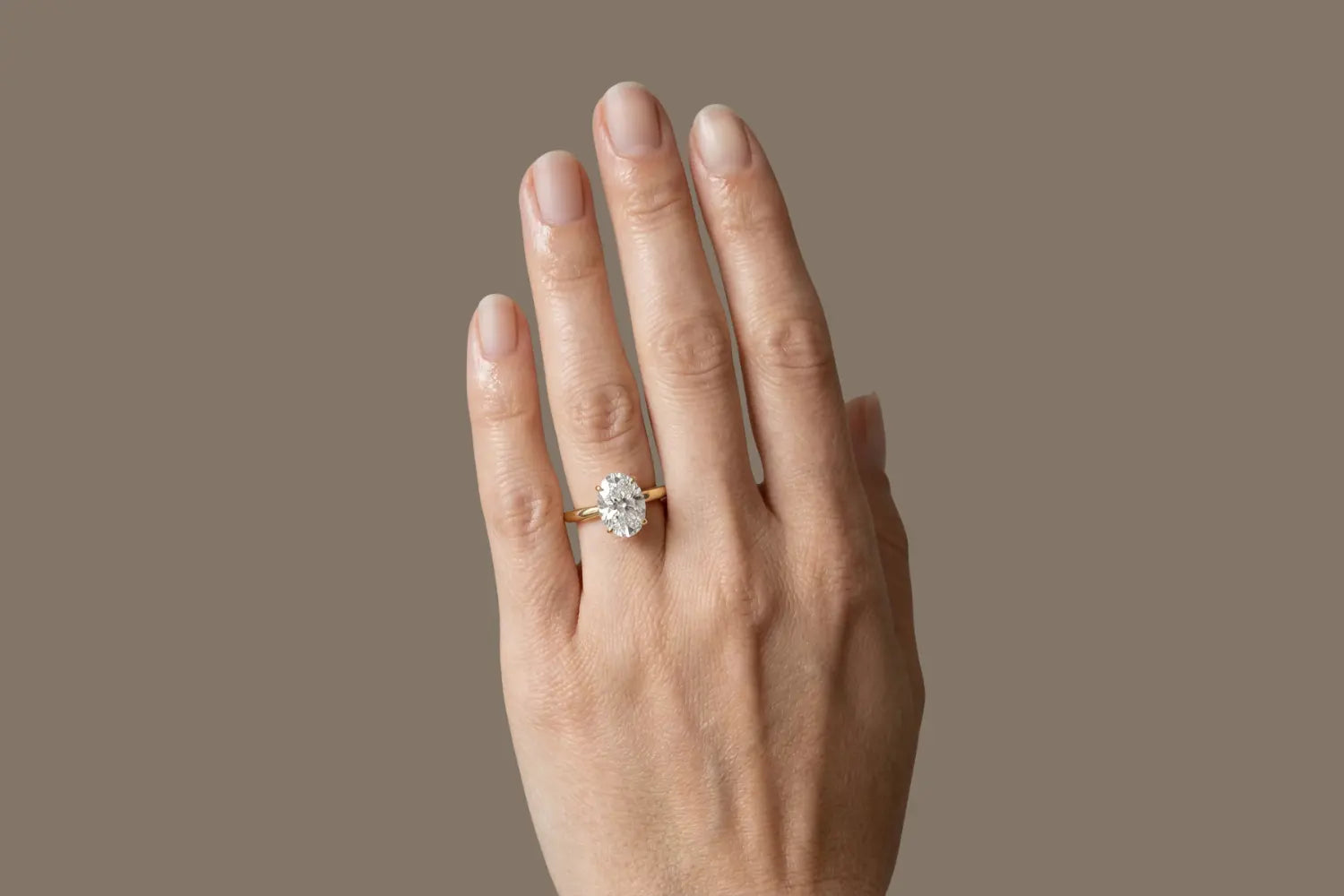 Forlovelsesring i gult gull med oval lab-diamant sett på hånd